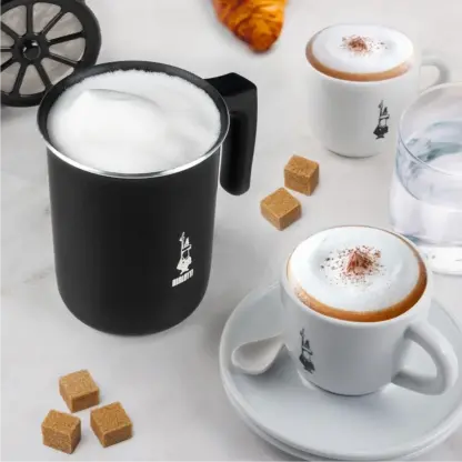 Bialetti Tuttocrema Manual Milk Frother full of frothed milk and two cappuccinos