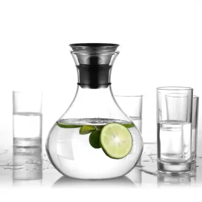 Clear Glass Pitcher With Handle on a table top filled with water with slices of lime.