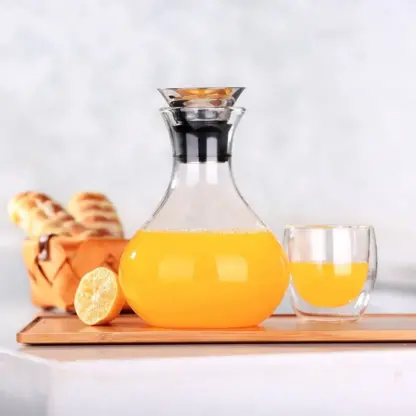 Clear Glass Pitcher With Handle on a tray with orrange juice, glass with orrange juice and bread in a basket