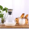 Clear Glass Pitcher With Handle on tray filled with milk and glass of milk next to it