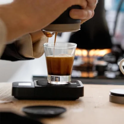 Picopresso Portable Espresso Machine in an indoors setting with a espresso glass on a scale