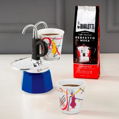 Bialetti Mini Express Kandinsky Moka Pot with one cup on the platform and another next to filled with coffee and a bag of Bialetti perfetto moka coffee.