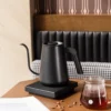 Gooseneck Pour-Over Kettle With Precision Temperature Control on table with a jug of coffee and coffee beans on table