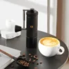 Chestnut S3 Portable Manual Coffee Grinder on table with a cappuccino in the foreground