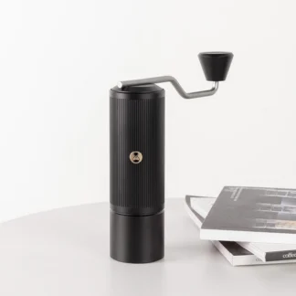 Chestnut X-lite Manual Portable Coffee Grinder on a table next to a stack of books