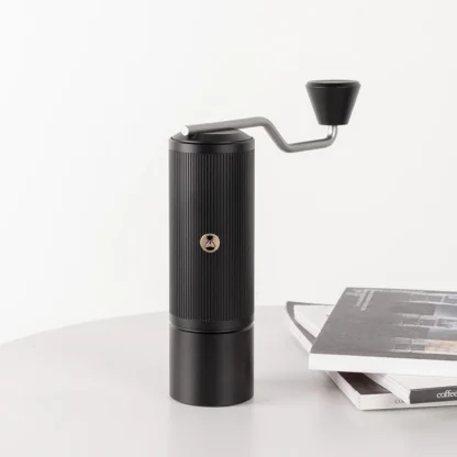 Chestnut X-lite Manual Portable Coffee Grinder on a table next to a stack of books