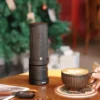 Millab 01 Portable Electric Coffee Grinder on a table with a cappuccino in the foreground