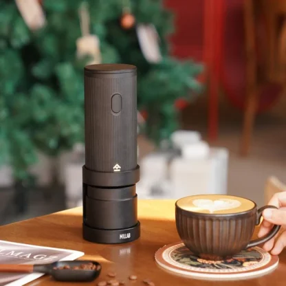 Millab 01 Portable Electric Coffee Grinder on a table with a cappuccino in the foreground